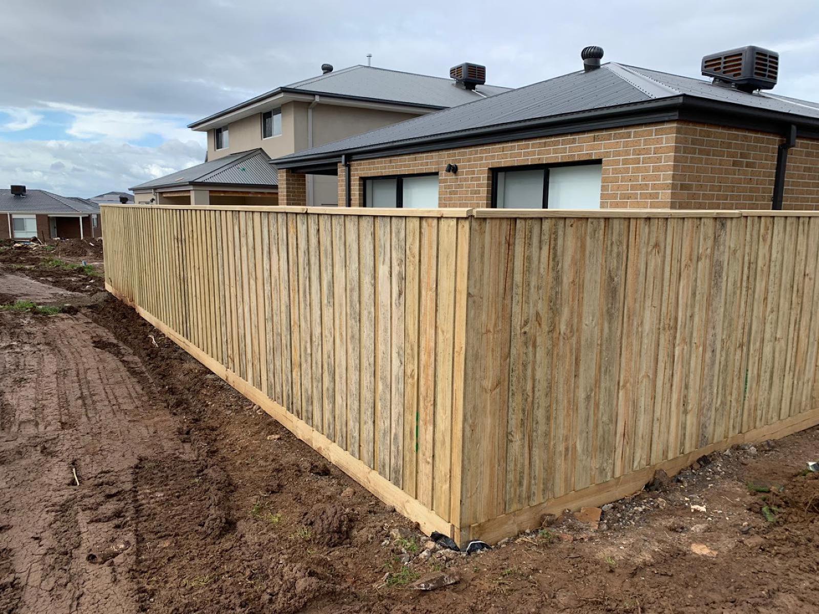 New timber paling fence around a brick home on a fresh build site
